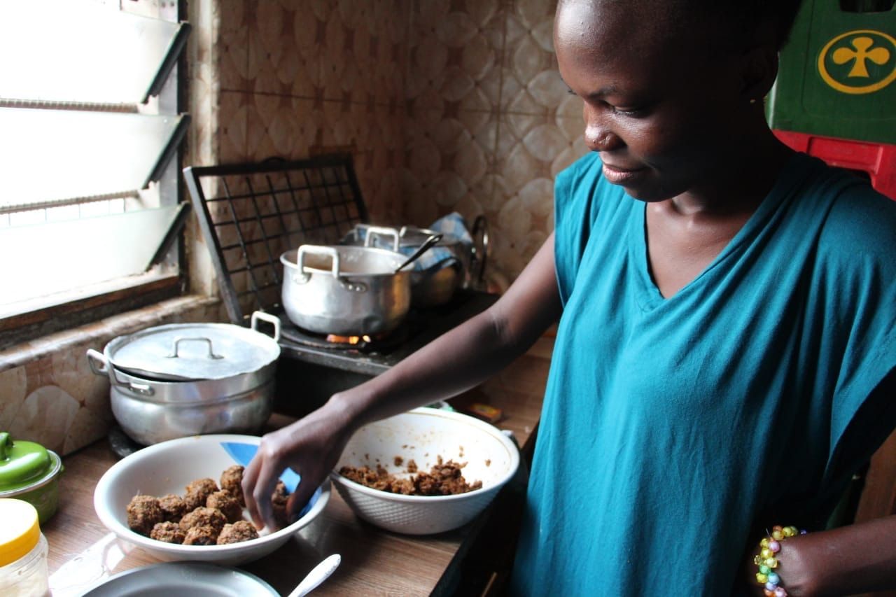 A cook shaping mince into balls in a home kitchen.
