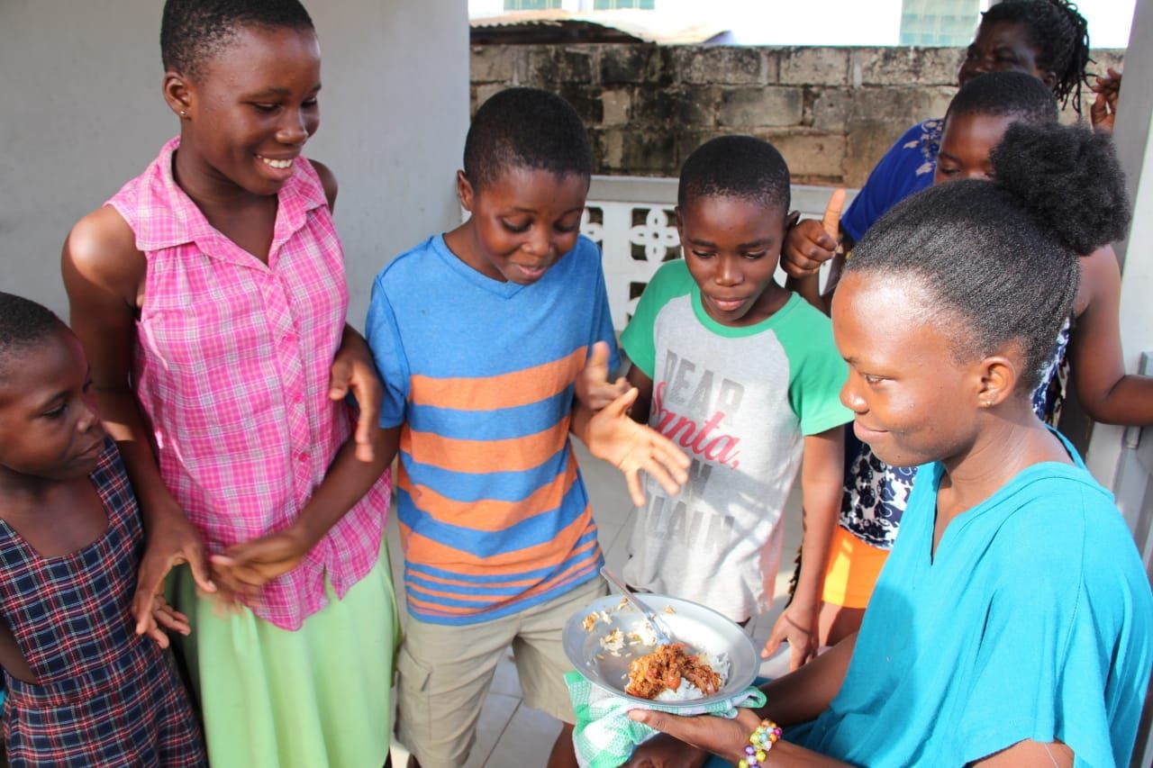 Children gathered around a shared plate of food.